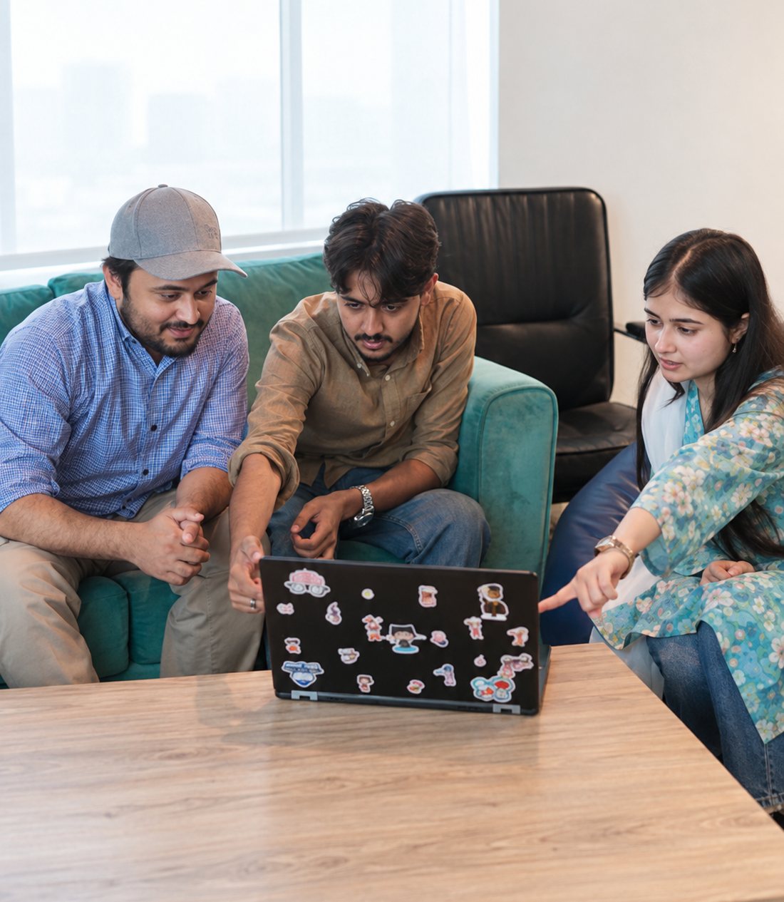 Three HexaClicks colleagues gathered around a laptop on the office sofa.